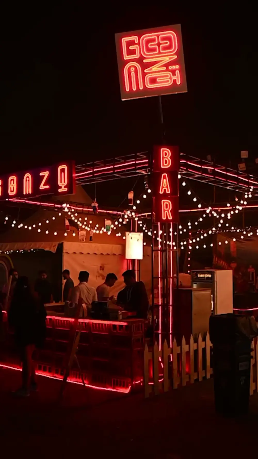 A bar lit with red neon and festoon lights at night