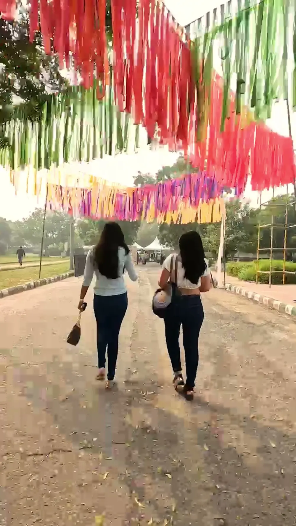 Two friends walking under colourful bunting in daylight