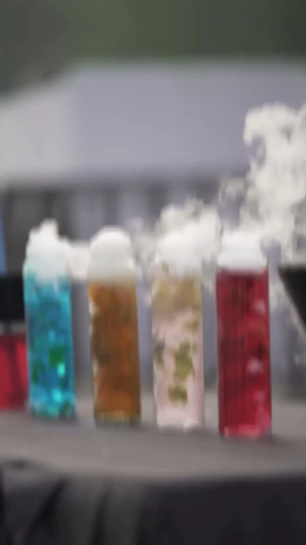 A row of colourful drinks in tall glasses