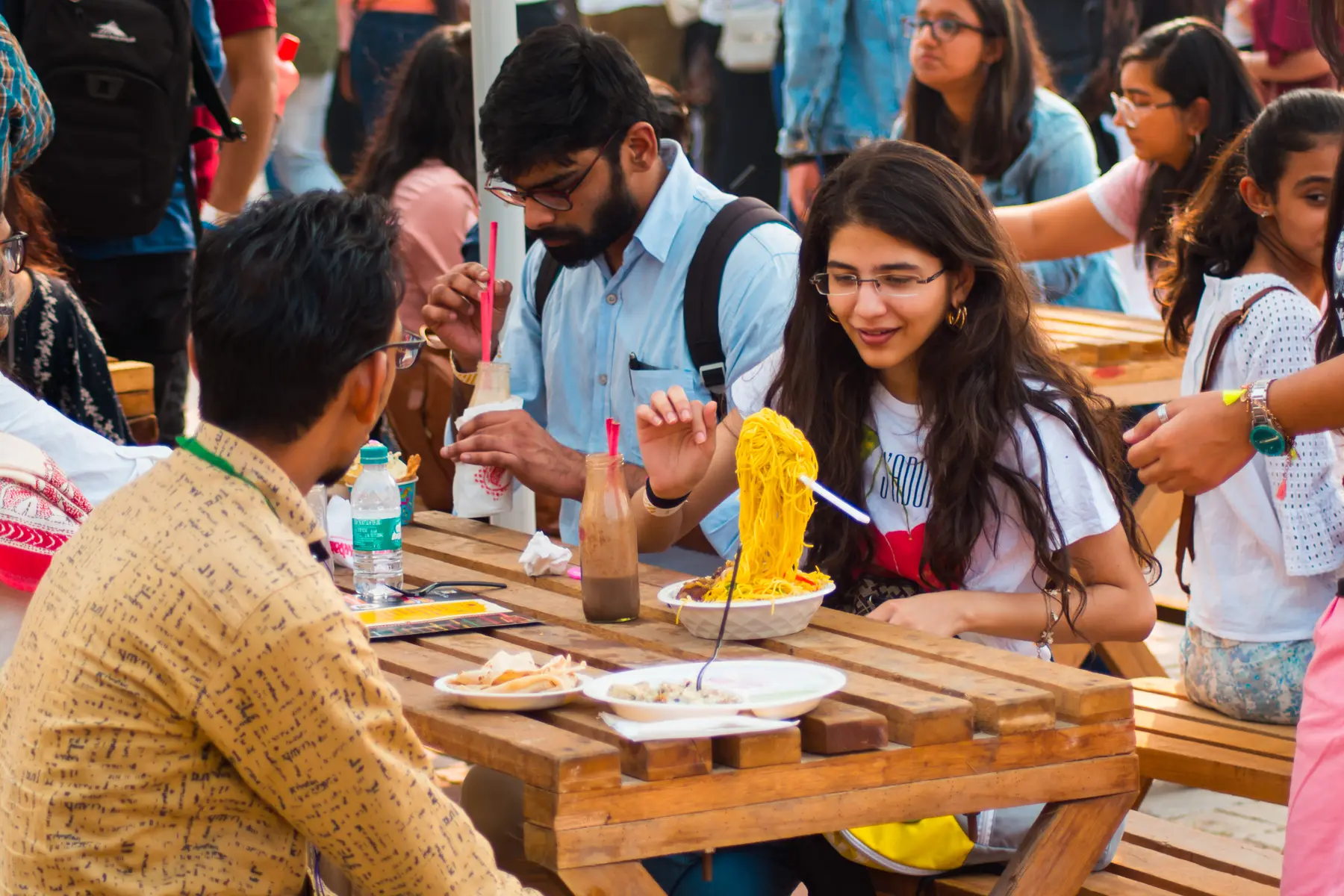 Guests eating noodles at a wooden table